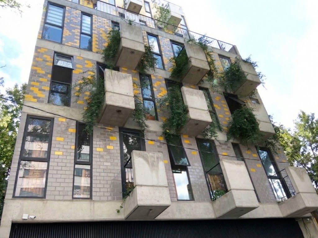 Fachada de tabique cerámico vidriado en gradiente bicolor con jardineras de concreto